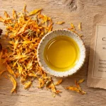 Photo huile végétale calendula : huile support ambrée et pétales de souci